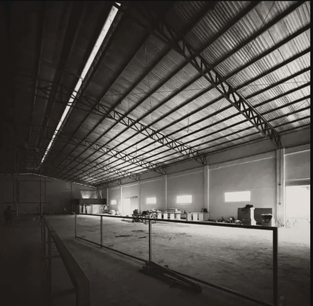 The South Dinkers warehouse mid-construction — steel trusses spanning a wide open floor that will become five courts